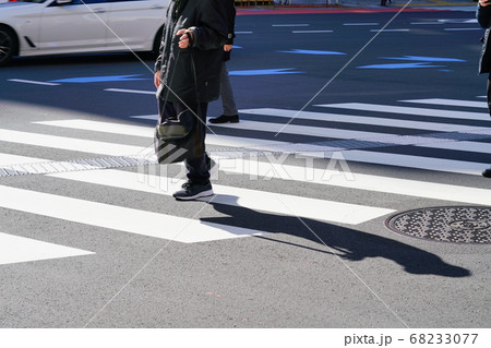 横断歩道を歩く人の足取りと影 68233077
