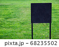 Closeup black metal sign at green grass background, nameplate with a space for your text, copyspace, empty space for inscription 68235502