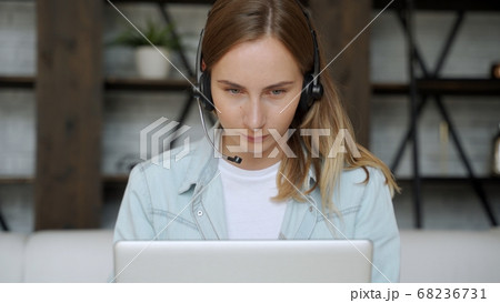 Young woman with a headset working online on computer while sitting at home. Concept of studying or working from home online 68236731