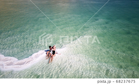 loving couple is resting on the dead sea. Salt coastline, The sea in Israel dies out and dries up 68237675