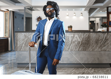 Black businessman with packed luggage standing in hotel lobby 68238611