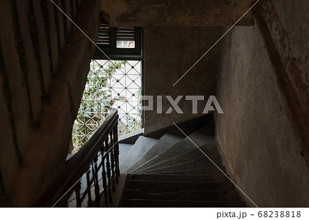 Dark stair descent in an old house with natural light coming from a barred window. The Mansion or Villa Bodega, Phnom Penh, Cambodia. 68238818