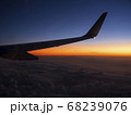 旅客機からの夕焼けの風景を見ながら帰路に就く 68239076