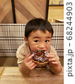 チョコレートドーナツを頬張る3歳の男の子 68244903