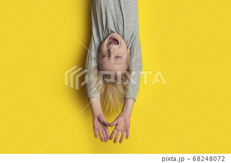 Funny fair-haired boy hanging upside down with 68248072