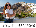 Happy smiling woman tourist traveling on luxury cruise in Mediterranean, Greece, Santorini. Female with folded arms, background architecture island sea sky 68249046