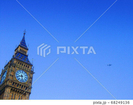 英国ロンドンの青空を背景にしたビッグベンの文字盤と飛行機の写真素材
