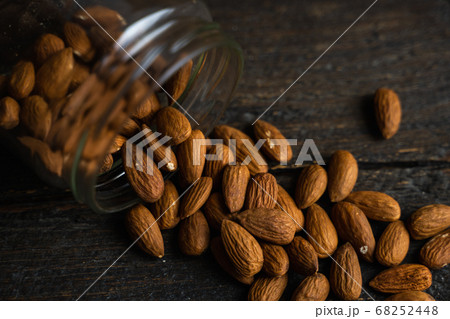 Almonds scattered on the wooden vintage table from a jar. Almond is a healthy vegetarian protein nutritious food. Almonds on rustic old wood. Almonds scattered on the wooden vintage table from a jar. Almond is a healthy vegetarian protein nutritious food. Almonds on rustic old wood. 68252448