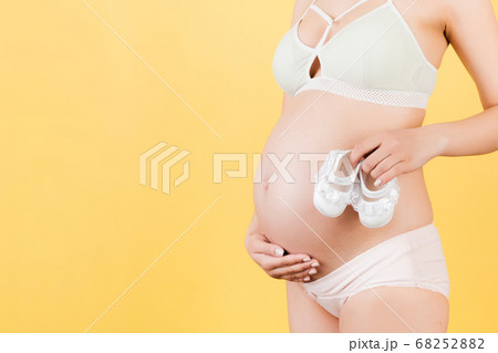 Close up of pregnant woman holding a pair of shoes 68252882