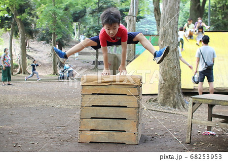 屋外の跳び箱を高く飛ぶ男の子の写真素材