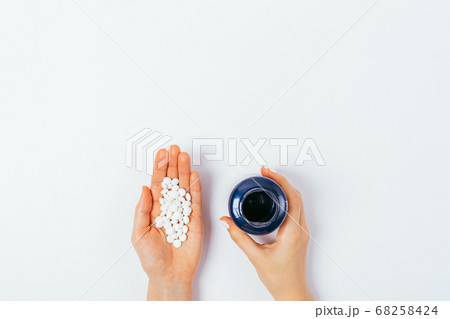 Woman's palm with handful of pills and hand Woman's palm with handful of pills and hand 68258424