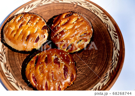 Butter buns with raisins and sesame seeds lie on a clay plate. Butter buns with raisins and sesame seeds lie on a clay plate. 68268744