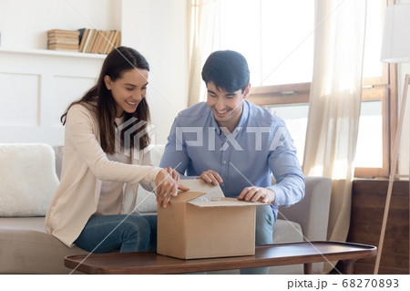 Happy young couple unpacking cardboard box at home. 68270893