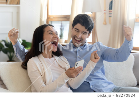 Overjoyed young family couple celebrating online lottery win. Overjoyed young family couple celebrating online lottery win. 68270924