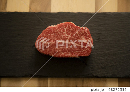 木の机の上の黒スレートに乗せた生の肉厚牛フィレステーキ 68272555