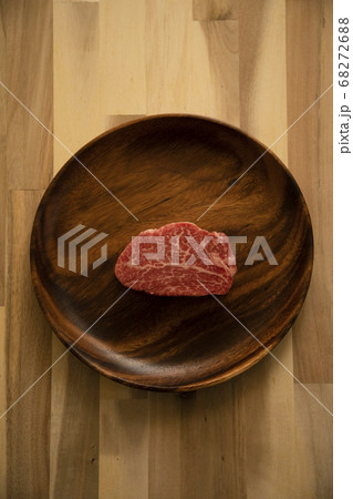 木の机の上のアカシアプレートに乗せた生の肉厚牛フィレステーキ 68272688