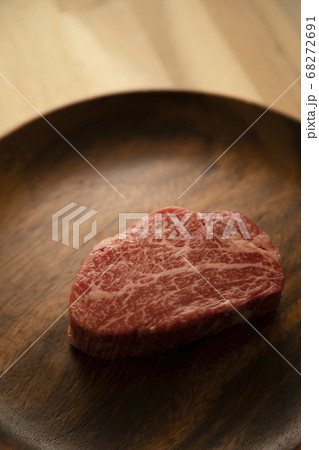 木の机の上のアカシアプレートに乗せた生の肉厚牛フィレステーキ 68272691
