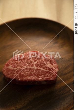 木の机の上のアカシアプレートに乗せた生の肉厚牛フィレステーキ 68272775