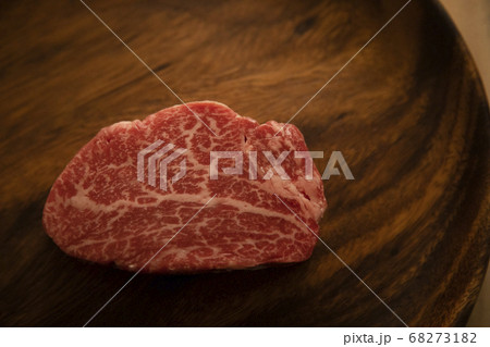 木の机の上のアカシアプレートに乗せた生の肉厚牛フィレステーキ 68273182