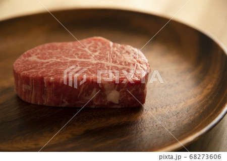 木の机の上のアカシアプレートにのせた生の肉厚牛フィレステーキ 木の机の上のアカシアプレートにのせた生の肉厚牛フィレステーキ 68273606