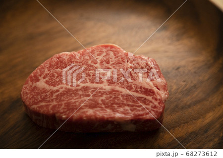 木の机の上のアカシアプレートにのせた生の肉厚牛フィレステーキ 68273612