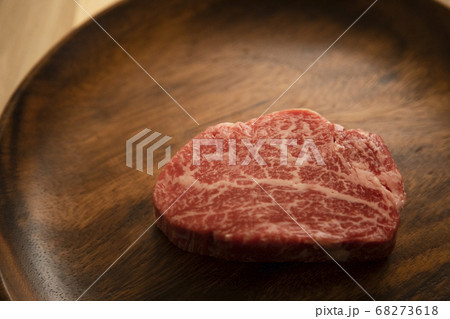 木の机の上のアカシアプレートにのせた生の肉厚牛フィレステーキ 68273618