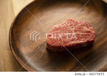 木の机の上のアカシアプレートに乗せた生の肉厚牛フィレステーキ 木の机の上のアカシアプレートに乗せた生の肉厚牛フィレステーキ 68273655