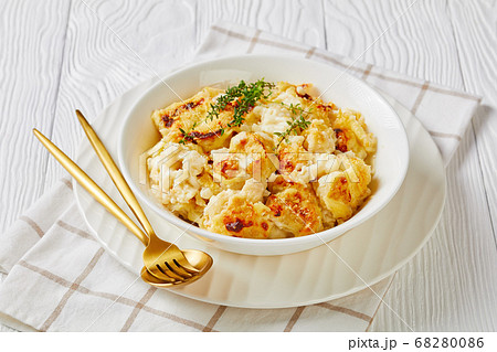 Vegan cauliflower cheese gratin on a white plate Vegan cauliflower cheese gratin on a white plate 68280086