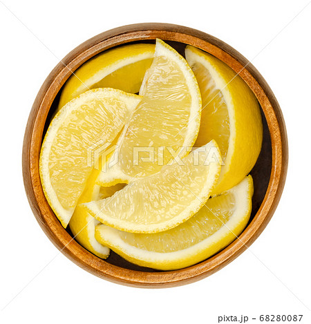 Lemon half in wooden bowl. Freshly cut ripe yellow edible citrus fruit. Citrus limon. Lemon juice is used for culinary purposes and for cleaning. Close up, from above, over white, isolated food photo. 68280087