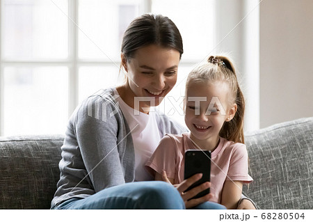 Smiling young mother showing funny mobile application to kid. Smiling young mother showing funny mobile application to kid. 68280504