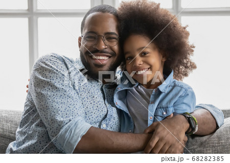 Portrait of smiling biracial dad and daughter cuddling Portrait of smiling biracial dad and daughter cuddling 68282385