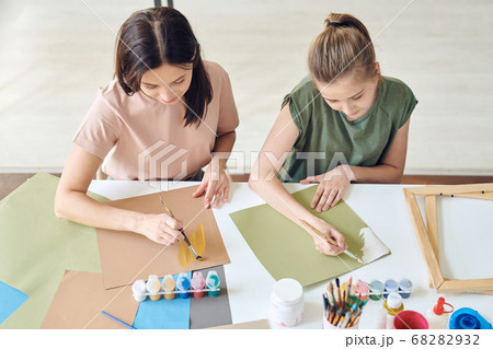 Young woman and her teenage daughter with paintbrushes painting with watercolors 68282932