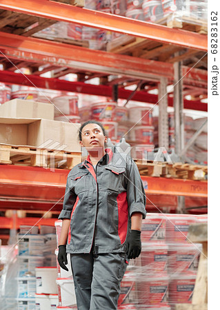 Young female worker of contemporary warehouse in uniform and gloves Young female worker of contemporary warehouse in uniform and gloves 68283162