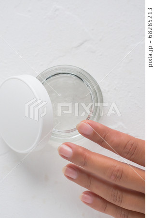 A woman's hand with a jar of face cream on a white 68285213