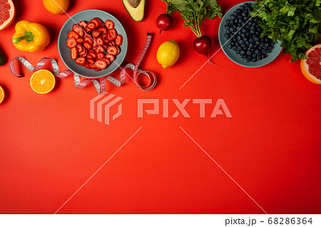 Diet concept. Healthy food and measuring tape on red background with border. Copy space top view. Diet concept. Healthy food and measuring tape on red background with border. Copy space top view. 68286364