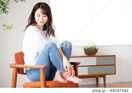 リビングで椅子の上にあぐらをかいて座る若い女性の写真素材 6874