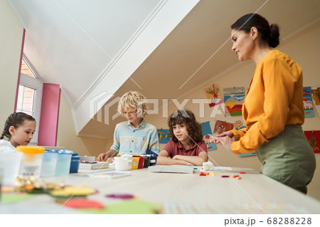 Cheerful kids enjoying art lesson with teacher Cheerful kids enjoying art lesson with teacher 68288228
