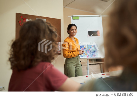 Happy pretty woman enjoying art lesson with pupils Happy pretty woman enjoying art lesson with pupils 68288230