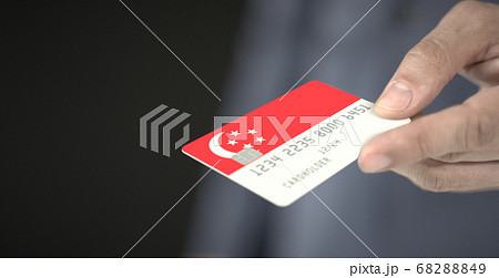Man gives credit card with printed flag of Singapore. Fictional numbers 68288849