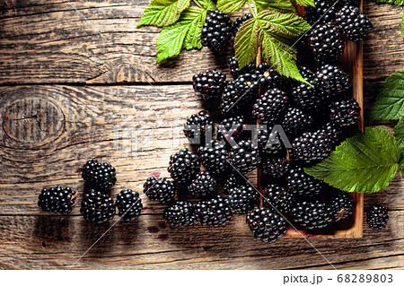 Ripe juicy blackberries with leaves on a wooden Ripe juicy blackberries with leaves on a wooden 68289803