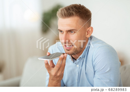 Young handsome man using voice assistant on smartphone Young handsome man using voice assistant on smartphone 68289983