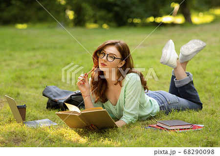 Portrait Of Dreamy Student Girl In Eyeglasses Studying Outdoors, Reading Book Portrait Of Dreamy Student Girl In Eyeglasses Studying Outdoors, Reading Book 68290098