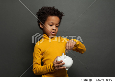 Black child boy putting in piggy bank euro coin Black child boy putting in piggy bank euro coin 68291045