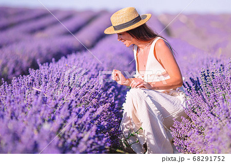 Woman in lavender flowers field at sunset in white dress and hat Woman in lavender flowers field at sunset in white dress and hat 68291752