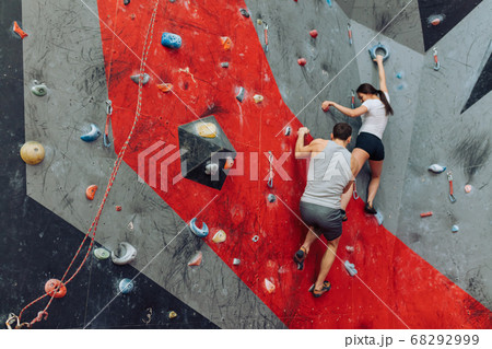 Dark-haired woman grabbing a handhold on the rock wall. 68292999