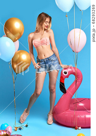 slim graceful charming girl with long blonde looking at inflatable flamingo. slim graceful charming girl with long blonde looking at inflatable flamingo. 68293269