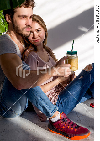 beautiful girl and handsome bearded guy are sitting on the floor 68293367