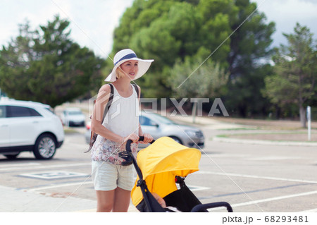 Young mother pushing stroller with sleeping baby outdoors 68293481