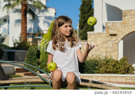 Girl child tossing, playing, juggling green apples, sunny summer day 68293859