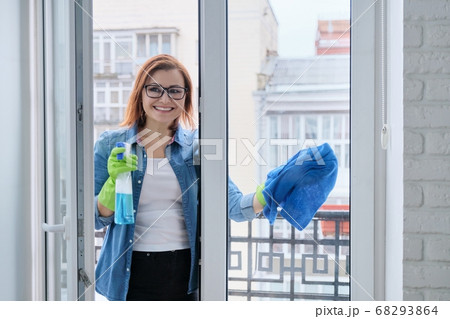 Mature woman cleaning windows at home in spring Mature woman cleaning windows at home in spring 68293864